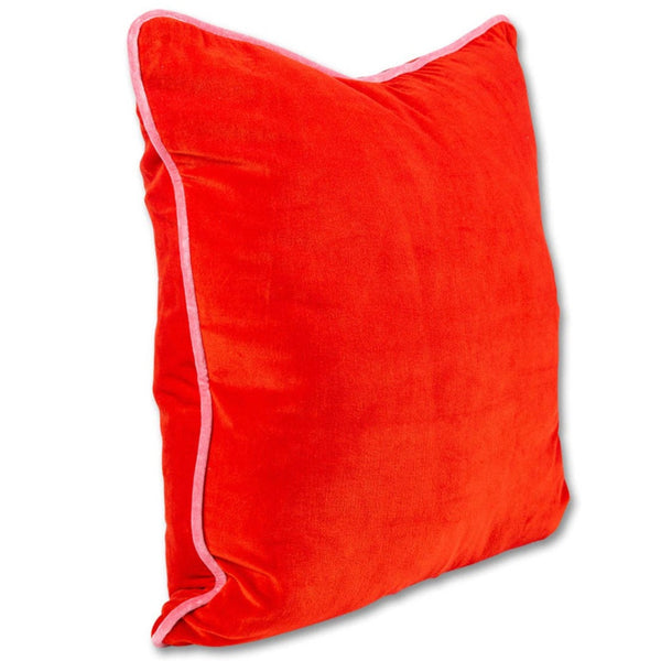 A bright red velvet square pillow with pink trim on the edges