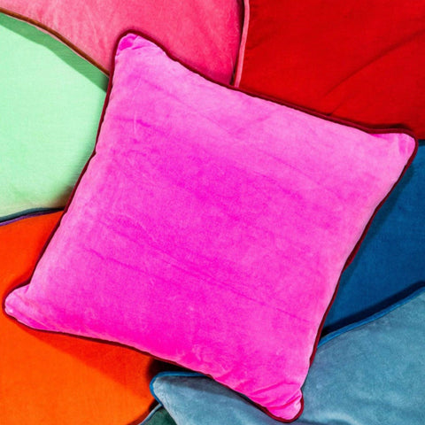 A hot pink velvet pillow with a deep red velvet trim